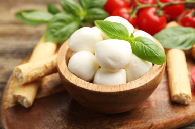 Lezzetli mozzarella peynir topları, domatesler, fesleğen ve Grissini masada, yakın plan.