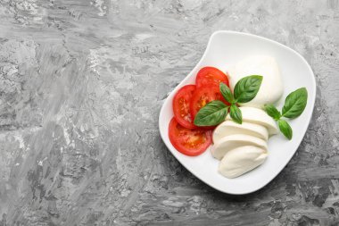 Lezzetli mozzarella peyniri, domates ve fesleğen gri masa, üst manzara. Metin için boşluk