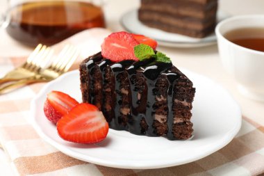 Çilek ve çayla servis edilen bir parça çikolatalı kek, yakın plan.