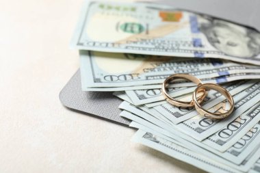 İki altın alyans, bir dolarlık banknotlar ve beyaz masanın üzerindeki zarf, yakın plan. Metin için boşluk