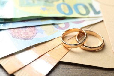 Altın alyanslar, zarf ve euro banknotları ahşap masa, yakın plan