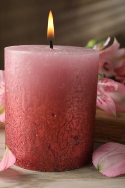 Yanan mum ve zambak çiçekleri beyaz ahşap masada, yakın plan