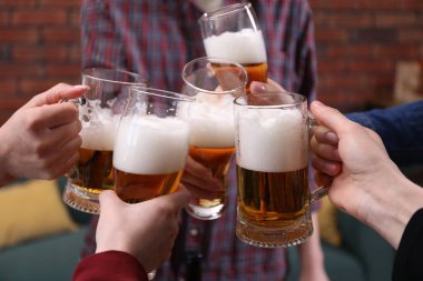 Arkadaşlar bira bardaklarını tokuşturur, yakın plan