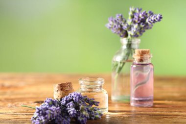 Ahşap masa üzerinde lavanta yağı ve çiçek şişeleri, yakın plan. Metin için boşluk