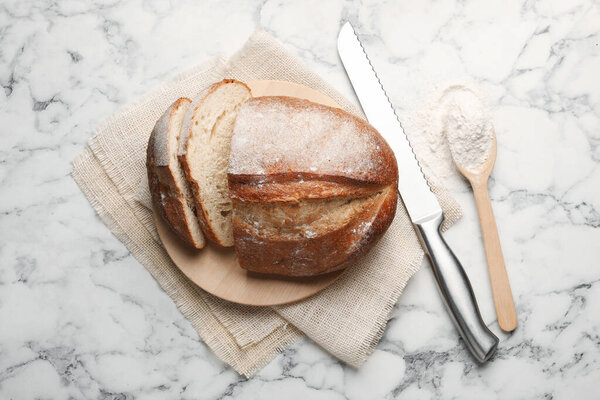 Кусочки свежего хлеба, муки и ножа на белом мраморном столе, плоская укладка
