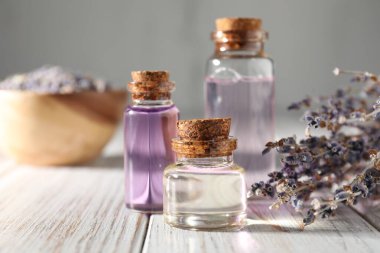 Beyaz ahşap masada doğal yağ ve lavanta çiçekleri, yakın plan.