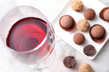 Bardakta kırmızı şarap ve ışık masasında yer mantarı şekerlemeleri.