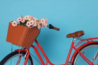 Açık mavi arka planda güzel çiçeklerle dolu bir bisiklet sepeti