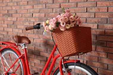 Bisiklet, içinde güzel çiçeklerle dolu bir sepet, duvarın içinde, yakın plan.