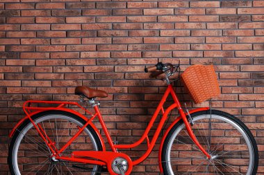 İçeride tuğla duvarın yanında sepeti olan kırmızı bir bisiklet. Metin için boşluk