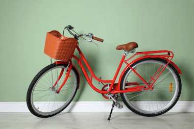 Açık yeşil duvarın yanında sepeti olan kırmızı bisiklet.