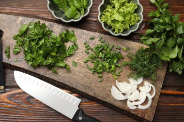 Farklı taze otlar, baharatlar ve bıçaklar ahşap masada, düz yerde.