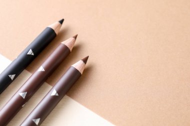 Bej arka planda farklı kaş kalemleri, düz yatış. Metin için boşluk