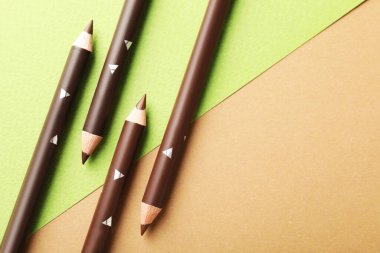 Renkli arka planda kahverengi kaş kalemleri, düz yatış. Metin için boşluk