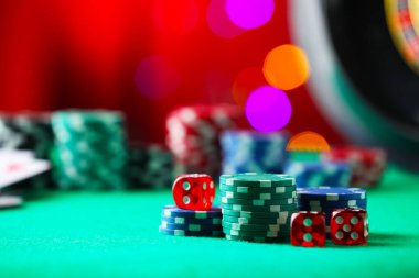 Kumarhane fişleri ve zarları yeşil masada bulanık ışıklara karşı, yakın plan