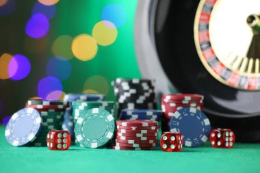 Kumarhane fişleri, zarlar ve rulet tekerleği yeşil masada bulanık ışıklara karşı, yakın plan