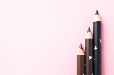 Pembe arka planda farklı kaş kalemleri, düz yatış. Metin için boşluk