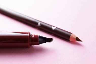 Pembe arka planda farklı kaş kalemleri, yakın plan.