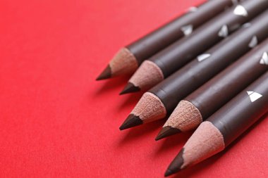 Kırmızı arka planda birçok kaş kalemi var, yakın plan. Metin için boşluk