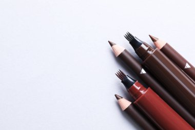 Beyaz arka planda farklı kaş kalemleri, düz yatış. Metin için boşluk