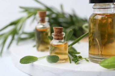 Beyaz masa üzerinde gerekli yağ ve bitkiler, yakın plan.