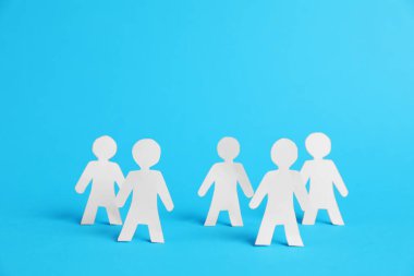Açık mavi arkaplanda insan kağıt figürleri