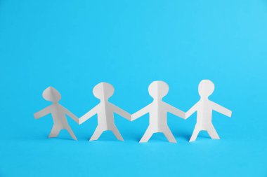 Açık mavi arka planda el ele tutuşan insan kağıt figürleri