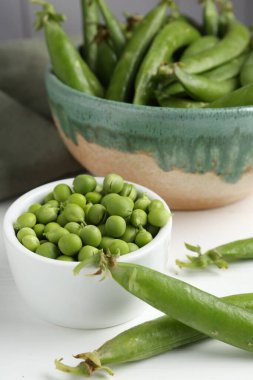 Taze taze bezelyeler beyaz ahşap masada, yakın plan.