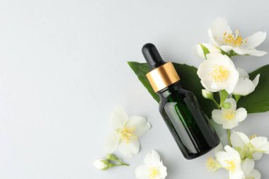 Kozmetik ürünleri ve yasemin çiçekleri arka planda, düz yerde. Metin için boşluk
