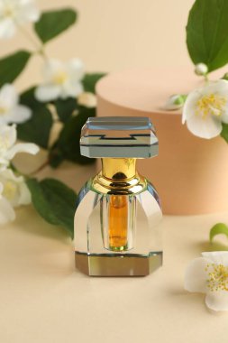 Bir şişe parfüm ve bej arka planda yasemin çiçekleri, yakın plan.