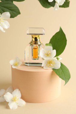 Bir şişe parfüm ve bej arka planda yasemin çiçekleri.