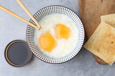 Kavanozda yarı haşlanmış yumurta, soya sosu, ekmek ve çubuklarla geleneksel Asya kahvaltısı.