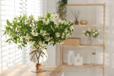 İçerideki ahşap masada vazoda duran bir buket güzel yasemin çiçeği. Metin için boşluk