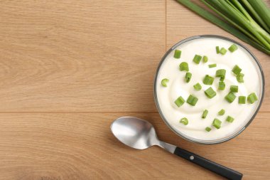 Kasede lezzetli yoğurt, yeşil soğan ve tahta masada kaşık, düz yatak. Metin için boşluk