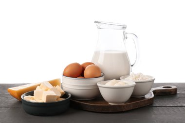 Gri ahşap masada beyaz arka planda farklı süt ürünleri ve yumurtalar