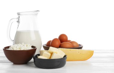 Farklı süt ürünleri ve yumurtalar beyaz arka plana karşı ahşap masa üzerinde