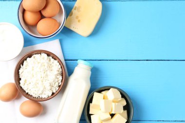Farklı süt ürünleri ve yumurtalar açık mavi ahşap masada, düz yerde. Metin için boşluk