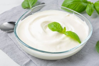 Lezzetli yoğurt ve fesleğen beyaz masada, yakın plan.