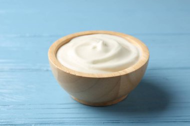 Açık mavi ahşap masadaki lezzetli yoğurt, yakın plan.