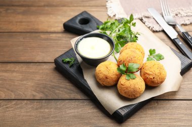 Maydanozlu ve ahşap masadaki soslu kızarmış köfteler.