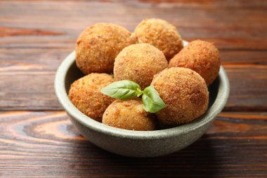 Tahta masadaki fesleğende fesleğen olan lezzetli kızarmış kroket topları, yakın plan.
