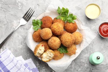 Gri desenli masada servis edilen maydanozlu ve soslu leziz kızarmış köfteler.