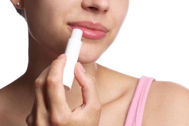 Beyaz arka planda dudak kremi olan genç bir kadın, yakın plan.