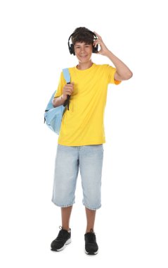 Beyaz arka planda sırt çantalı kulaklıklı genç bir çocuk.