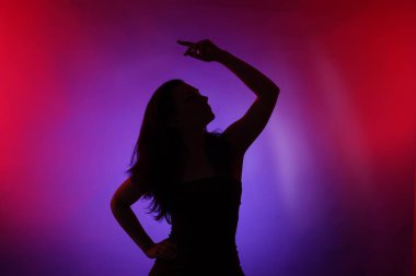 Renkli arka planda neon ışıklarla poz veren kadın silueti