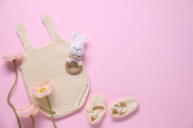 Bebek kıyafetleri, çiçekler ve pembe arka planda aksesuarlar, düz yatış. Metin için boşluk