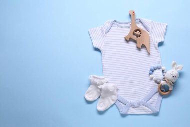 Açık mavi arka planda bebek kıyafetleri ve aksesuarlar, düz yatış. Metin için boşluk