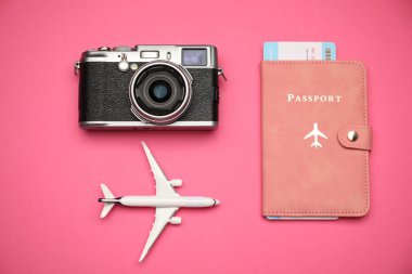 Uçak modeli, pasaport, uçuş bileti ve pembe arka planda klasik fotoğraf makinesi, düz konum