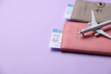 Uçak modeli, pasaportlar ve uçuş biletleri menekşe arka planda, yakın plan. Metin için boşluk