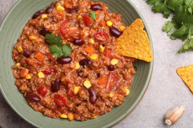 Lezzetli biberli makarna kasede ve nachos gri masada, düz yerde.